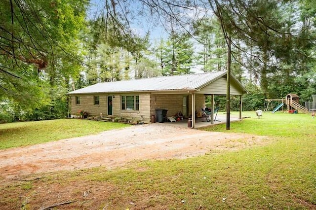 back of house featuring a lawn, a carport, and a playground