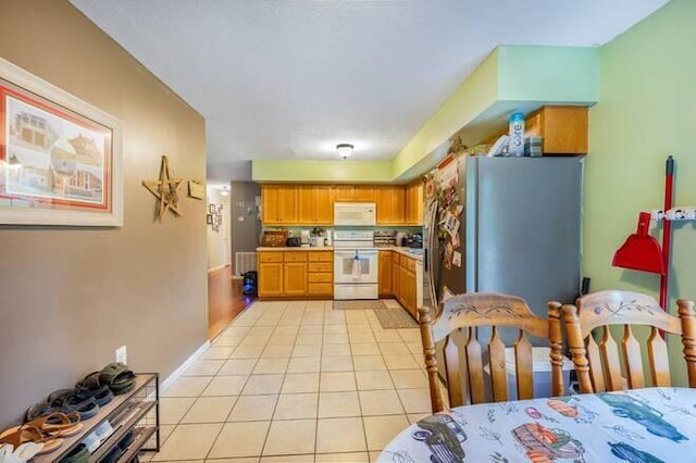 kitchen with decorative backsplash, stainless steel fridge, light tile patterned floors, and range