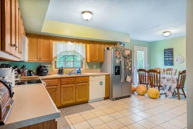 kitchen featuring stainless steel fridge, dishwasher, light tile patterned floors, and sink