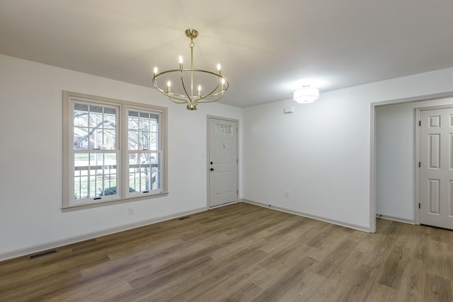 spare room featuring a chandelier and wood-type flooring