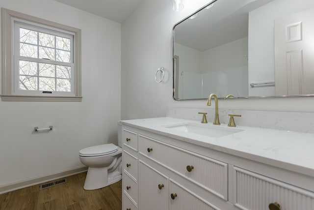 bathroom with a shower, hardwood / wood-style floors, vanity, and toilet