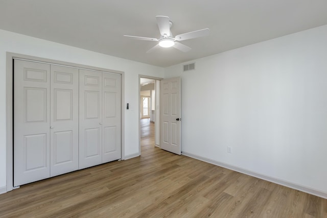 unfurnished bedroom featuring ceiling fan, light wood-type flooring, and a closet