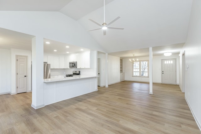 kitchen featuring stainless steel appliances, light hardwood / wood-style flooring, kitchen peninsula, white cabinets, and ceiling fan with notable chandelier