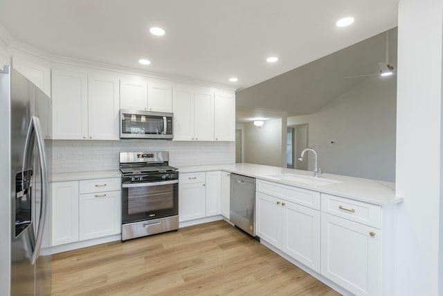 kitchen featuring kitchen peninsula, appliances with stainless steel finishes, tasteful backsplash, sink, and white cabinets