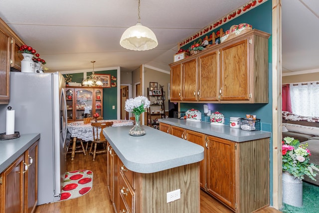 kitchen featuring a center island, hanging light fixtures, white refrigerator, vaulted ceiling, and light wood-type flooring