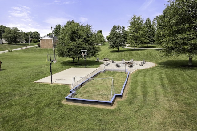 view of property's community featuring basketball hoop and a lawn