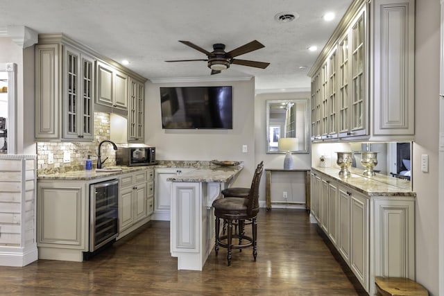 kitchen with a kitchen bar, light stone counters, tasteful backsplash, and beverage cooler