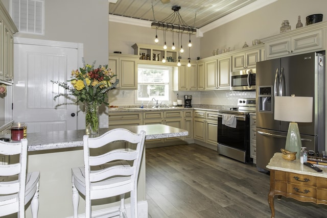 kitchen with backsplash, cream cabinets, hanging light fixtures, dark hardwood / wood-style floors, and appliances with stainless steel finishes