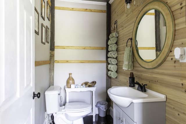 bathroom with wooden walls, vanity, and toilet