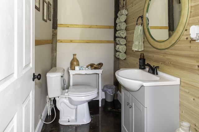 bathroom featuring vanity, toilet, and wood walls