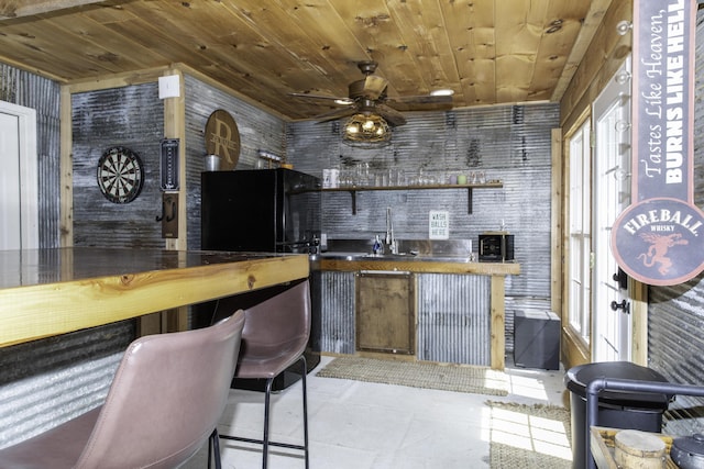 bar with black refrigerator, sink, tile patterned flooring, ceiling fan, and wood ceiling