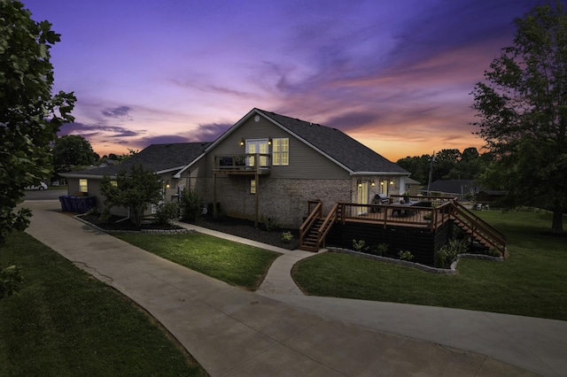 exterior space featuring a lawn, a balcony, and a wooden deck