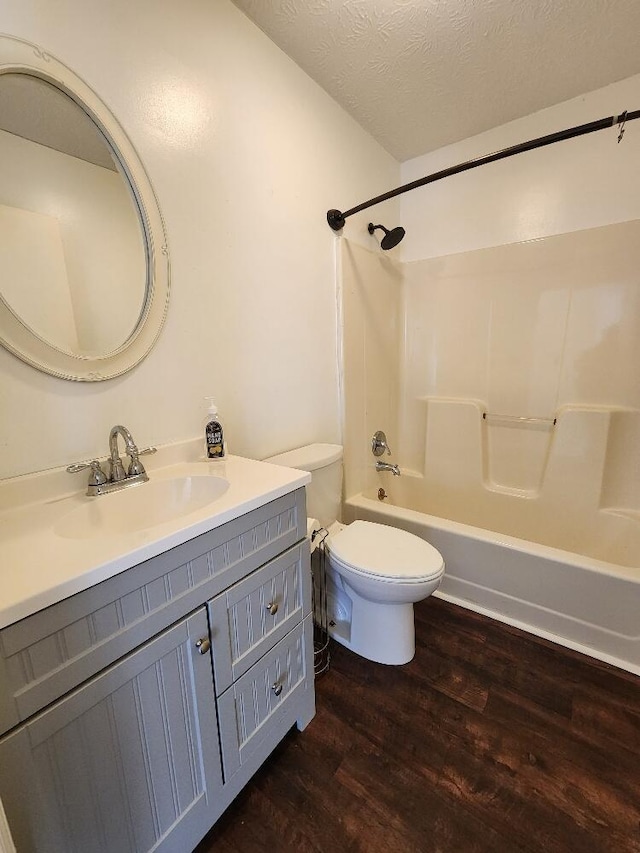 full bathroom featuring wood-type flooring,  shower combination, a textured ceiling, toilet, and vanity