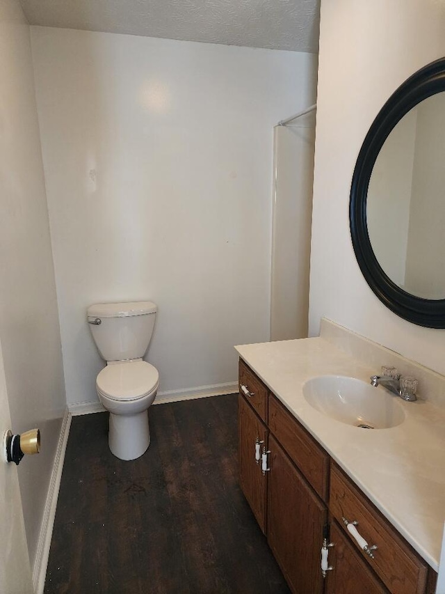 bathroom with vanity, wood-type flooring, a textured ceiling, and toilet