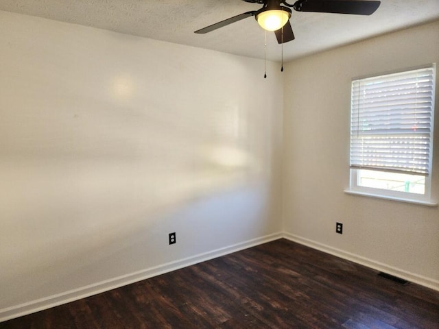 unfurnished room featuring plenty of natural light, dark wood-type flooring, and ceiling fan