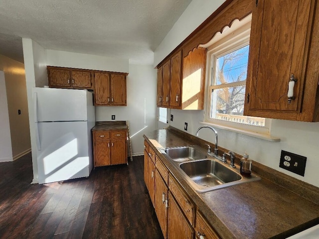 kitchen featuring a textured ceiling, dark hardwood / wood-style floors, white refrigerator, and sink