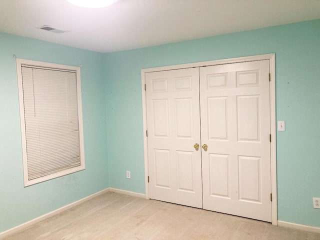 unfurnished bedroom with light colored carpet and a closet