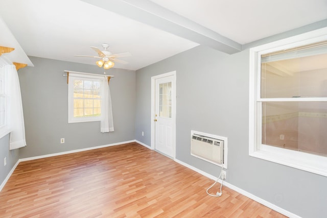 empty room with light wood-style floors, an AC wall unit, baseboards, and a ceiling fan