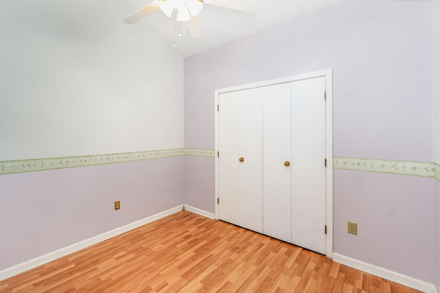 unfurnished bedroom featuring light wood finished floors, baseboards, lofted ceiling, ceiling fan, and a closet