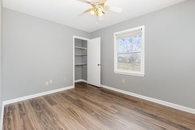 unfurnished bedroom with a closet, wood finished floors, a ceiling fan, and baseboards