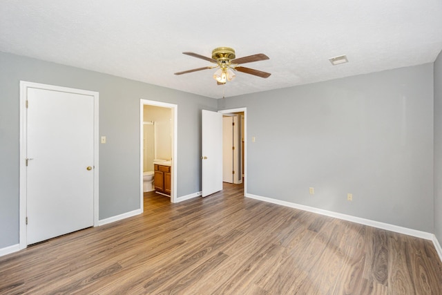 unfurnished bedroom featuring connected bathroom, wood finished floors, visible vents, and baseboards