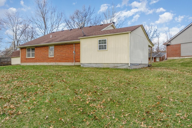 rear view of house featuring brick siding and a yard