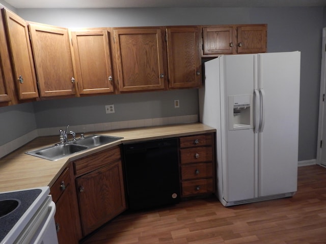 kitchen with light wood finished floors, light countertops, a sink, white fridge with ice dispenser, and dishwasher