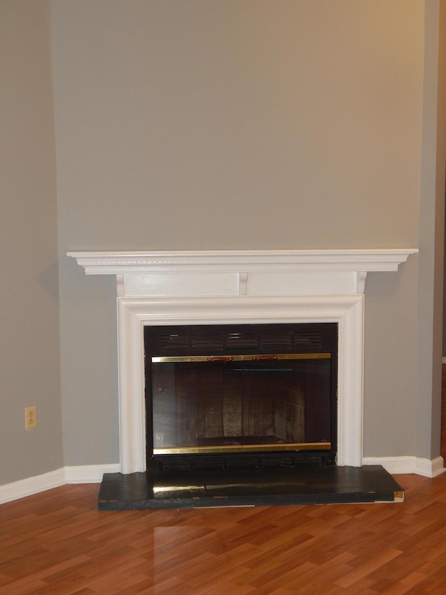 room details featuring wood finished floors, a glass covered fireplace, and baseboards