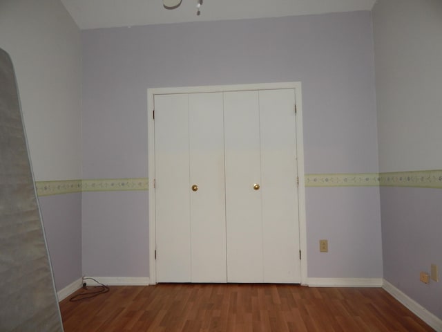 unfurnished bedroom featuring wood finished floors and baseboards