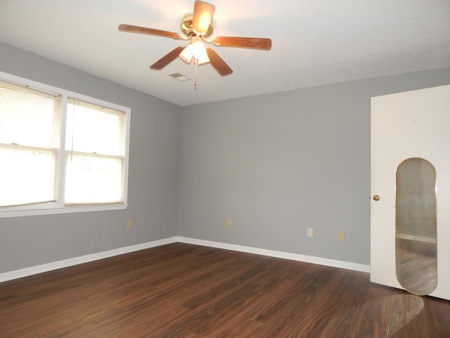 unfurnished room featuring ceiling fan, arched walkways, dark wood-type flooring, visible vents, and baseboards