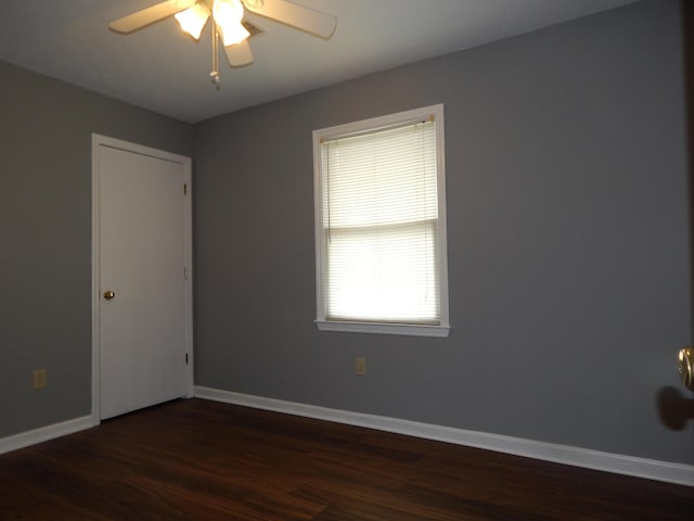 empty room featuring ceiling fan, dark wood finished floors, and baseboards