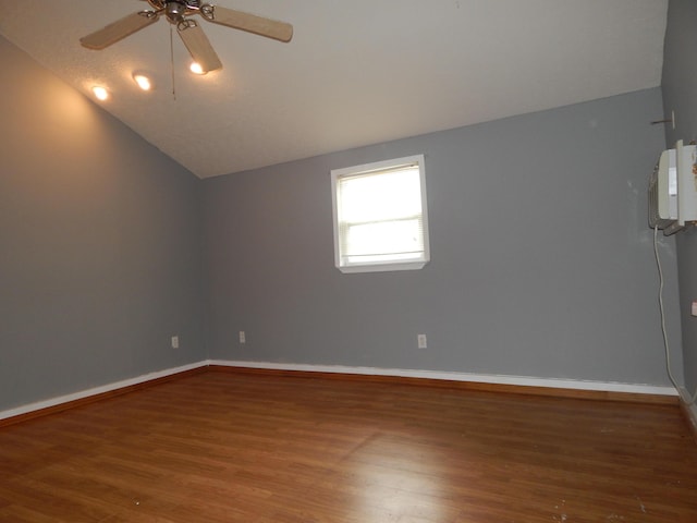 spare room featuring lofted ceiling, baseboards, and wood finished floors