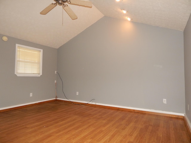 empty room featuring lofted ceiling, ceiling fan, light wood-type flooring, and baseboards