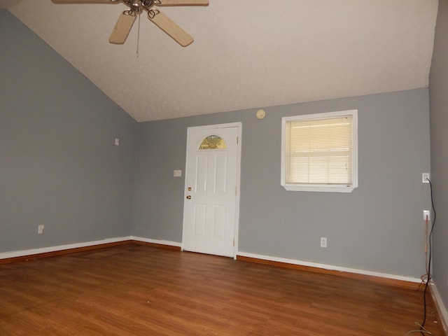 interior space with a ceiling fan, baseboards, vaulted ceiling, and wood finished floors