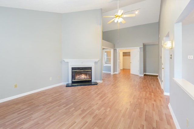 unfurnished living room with light wood-style floors, baseboards, and a glass covered fireplace