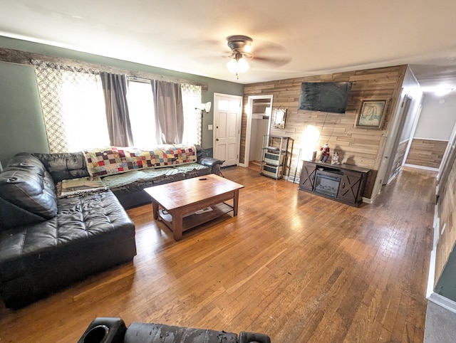 living room with wooden walls, hardwood / wood-style floors, and ceiling fan