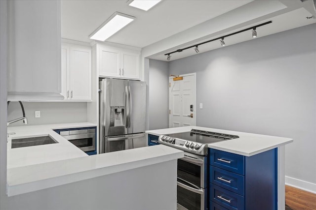 kitchen featuring stainless steel appliances, blue cabinets, dark wood-type flooring, sink, and white cabinetry