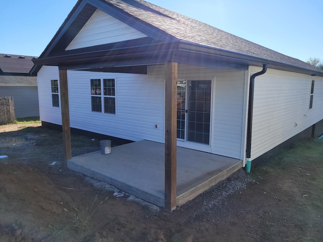 back of property with a patio and roof with shingles