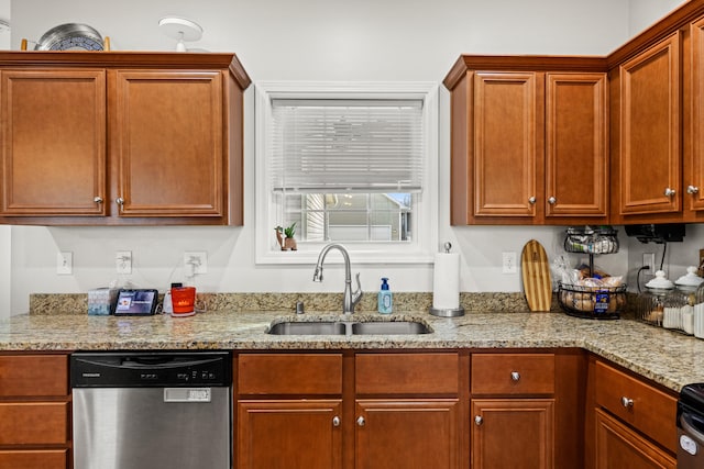 kitchen with stainless steel dishwasher, a sink, and light stone countertops