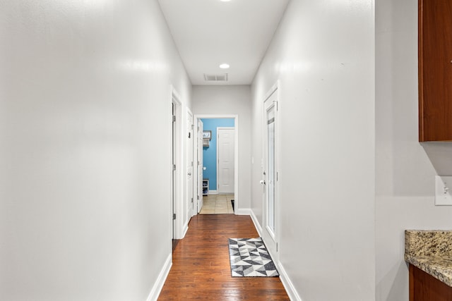 corridor with baseboards, visible vents, and wood finished floors