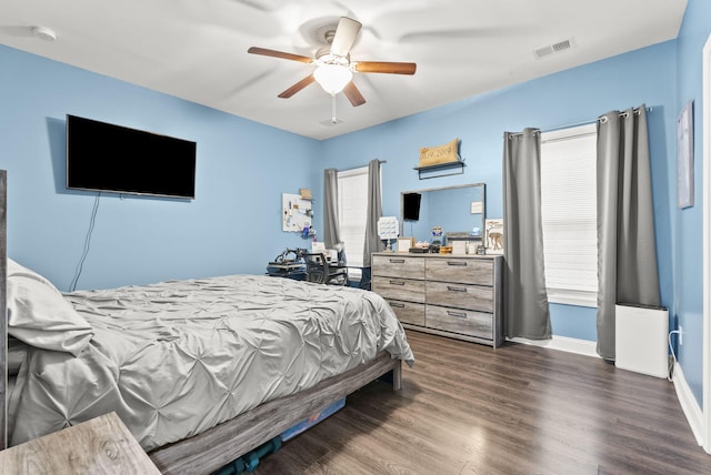 bedroom featuring ceiling fan, dark wood-style flooring, visible vents, and baseboards