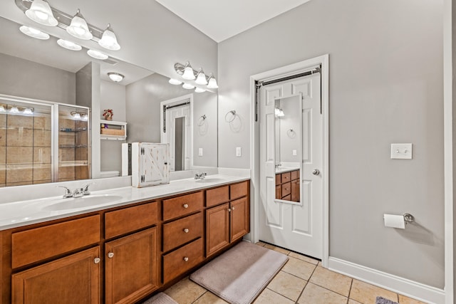 bathroom featuring double vanity, a stall shower, a sink, and tile patterned floors