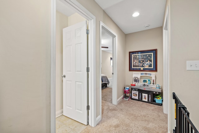 hall featuring light carpet and baseboards