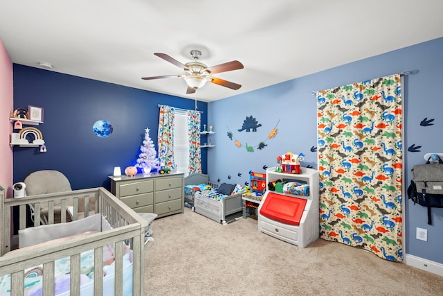 bedroom featuring a nursery area, carpet, and a ceiling fan