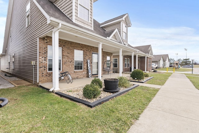 view of side of home with a lawn, a patio, and brick siding