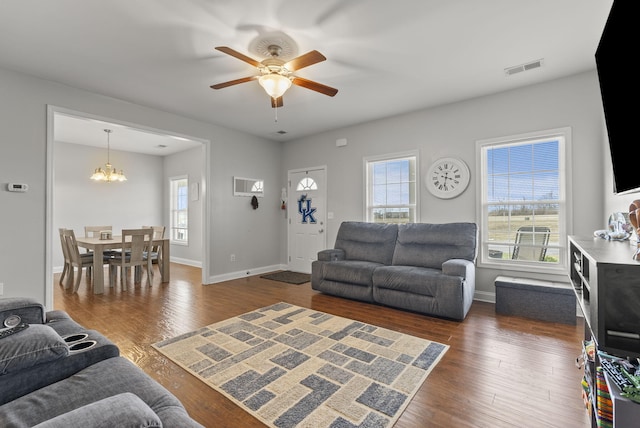 living room with dark wood-style flooring, visible vents, and baseboards