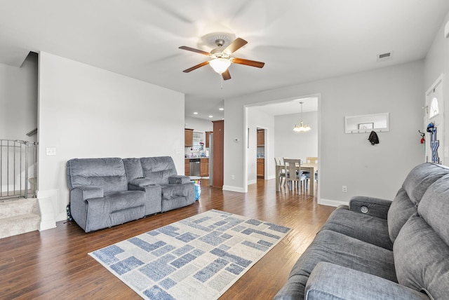 living room with dark wood-style floors, visible vents, baseboards, and ceiling fan with notable chandelier