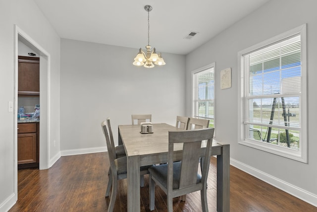 dining space with dark wood-style flooring, an inviting chandelier, visible vents, and baseboards