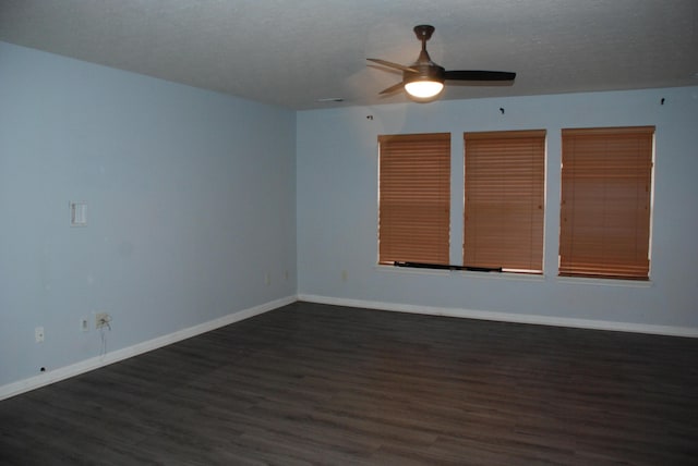 empty room featuring ceiling fan, dark wood-type flooring, and a textured ceiling