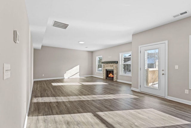 unfurnished living room with hardwood / wood-style floors and a stone fireplace